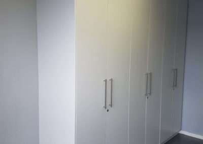 white built in cupboards with 6 doors from floor to ceiling
