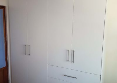 White bedroom built in cupboards with hanging space and draws on the side
