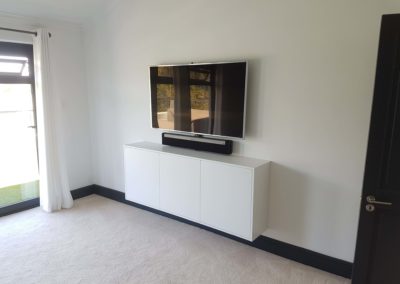3 door custom suspended TV entertainment unit in bedroom for widescreen TV with gloss white finish and no door handles