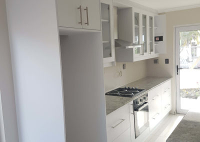 white kitchen cupboards with grey counters and clear glass doors 2