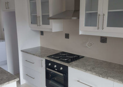 white kitchen cupboards with grey counters and clear glass doors