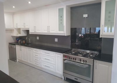 Custom kitchen remodel with white doors dark countertops and glass misted windows on doors 3