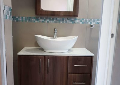 custom bathroom vanity with dark wood doors and light countertop with basin on top