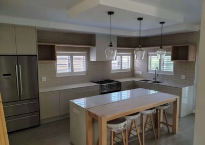 bespoke kitchen built with a custom island and seating with light countertops and white doors 8
