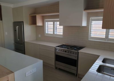 bespoke kitchen built with a custom island and seating with light countertops and white doors 6