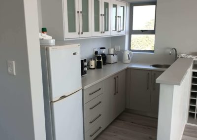 custom kitchenette with light grey cupboards and glass doors