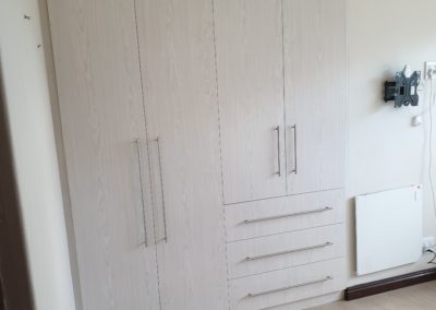 Light grey built in cupboards featuring hanging space and draws