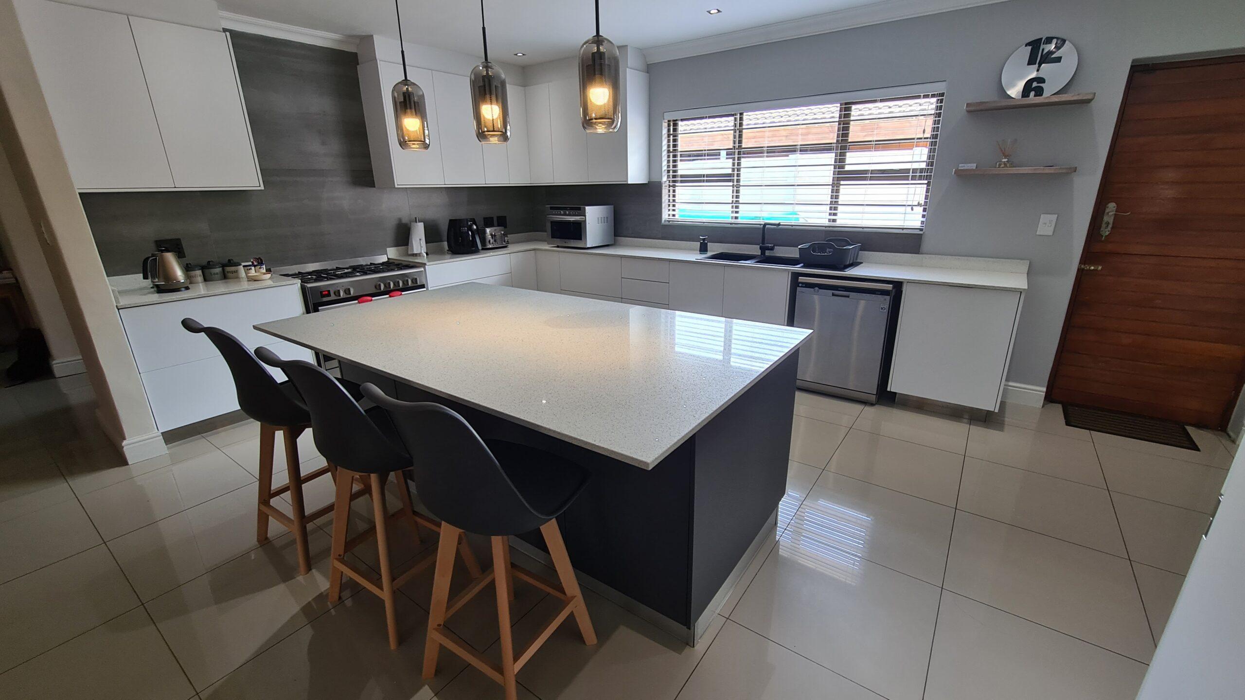 bespoke kitchen built with a custom island and seating with light countertops and white doors